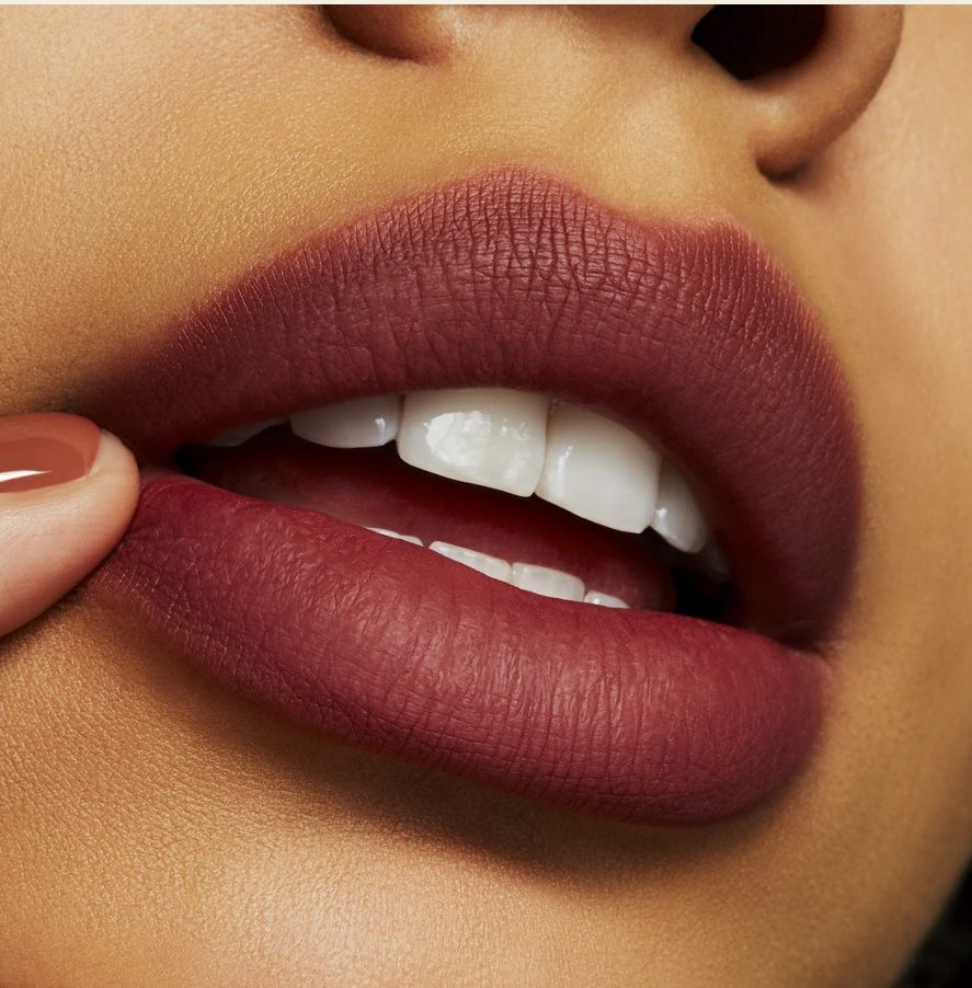 Extreme close-up of a person wearing a rich, matte berry-toned MAC lipstick.
