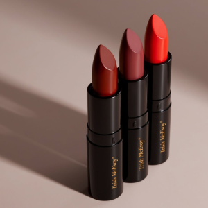 Three shades of Trish McEvoy luxury lipsticks in sleek black and gold tubes.