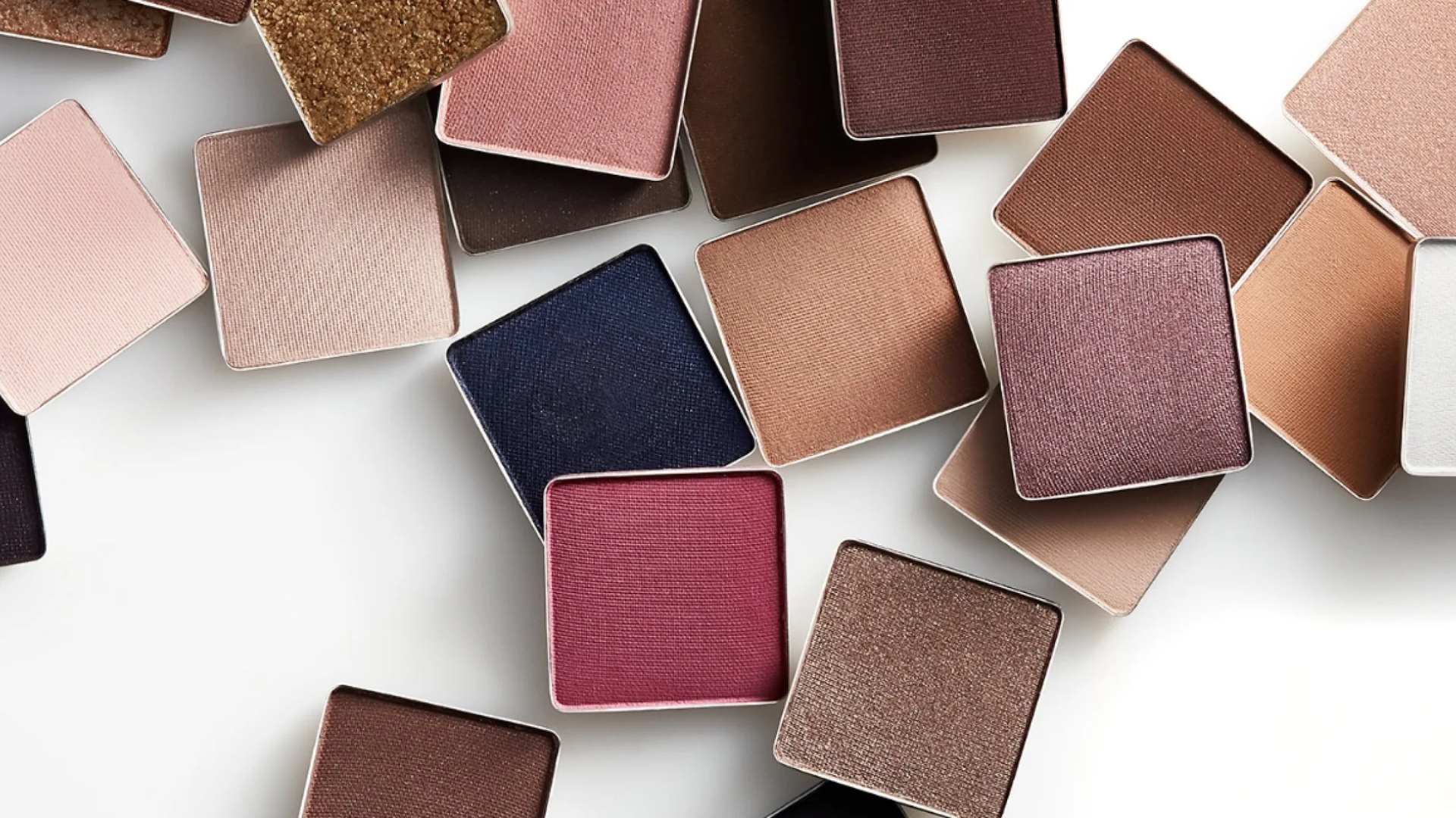 Flat lay of various Trish McEvoy colorful eyeshadow pans in neutral, berry, and shimmer tones for custom makeup palettes in New York.